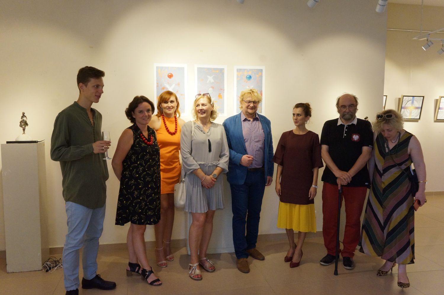 Zdjęcie przedstawia grupę osób stojących na tle obrazów wiszących na jasnych ścianach. Osoby są elegancko ubrane. To przedstawiciele Małopolski i Adżarii oraz artyści.