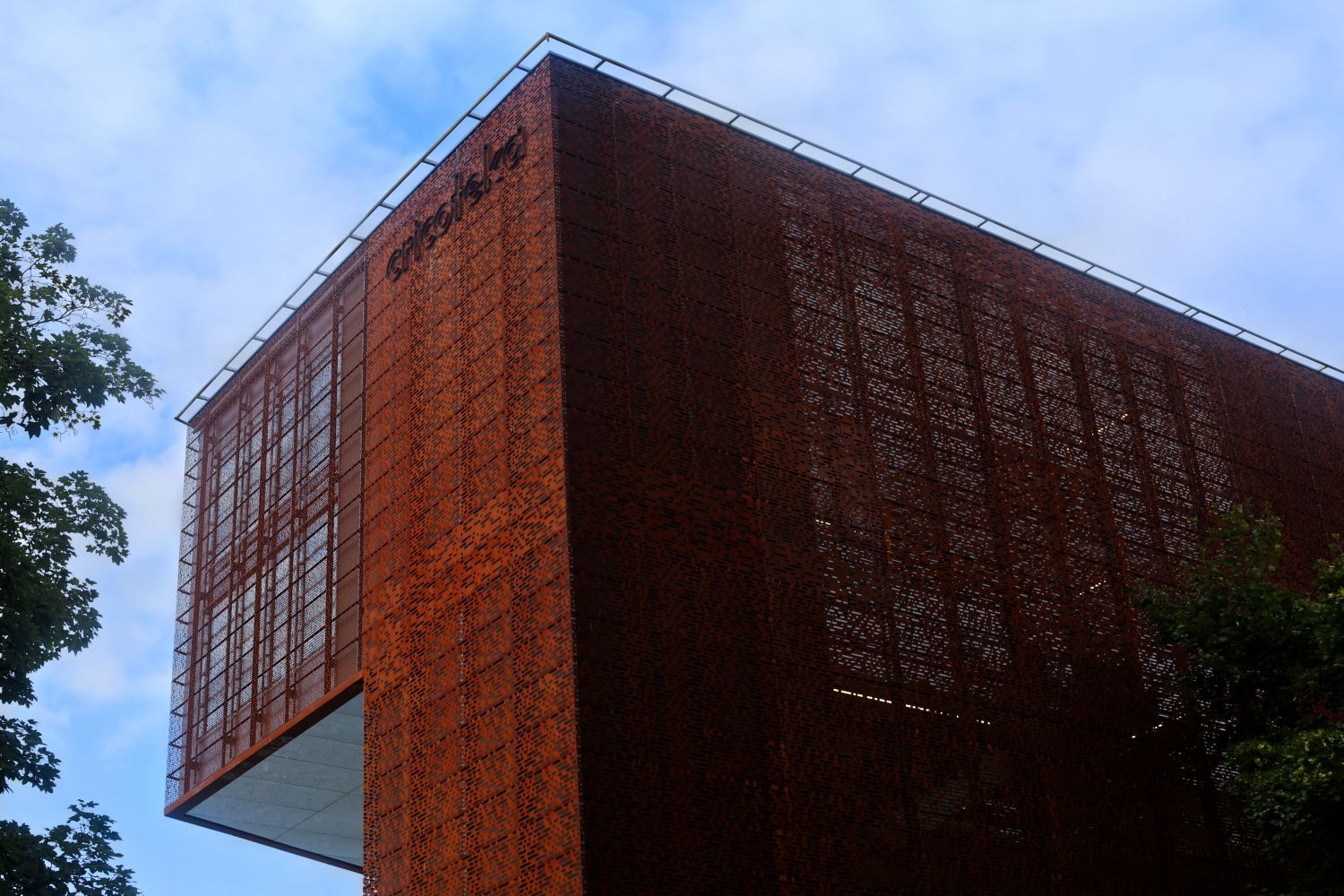 Fragment fasady budynku Cricoteki pokrytej spatynowaną perforowaną blachą na tle błękitnego nieba